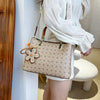 CJ floral pendant crossbody bag with beige pattern and brown leather handles worn by woman in white blouse