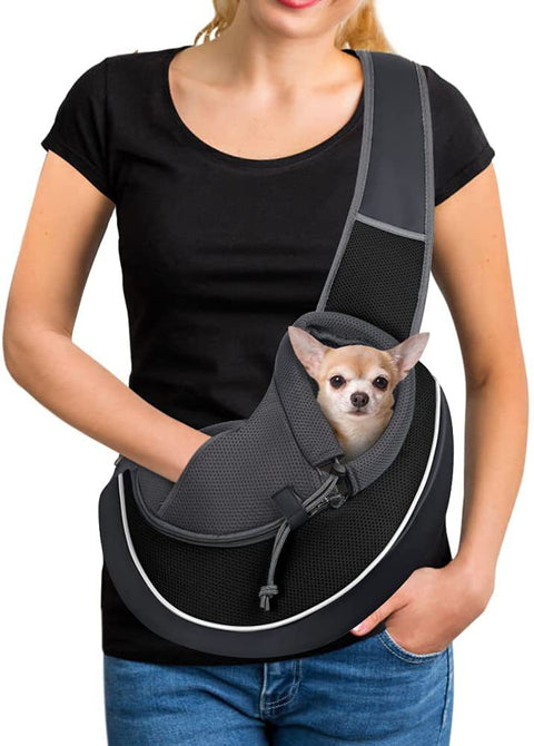 Portable pet carrier bag with small dog inside worn by person in black shirt and jeans